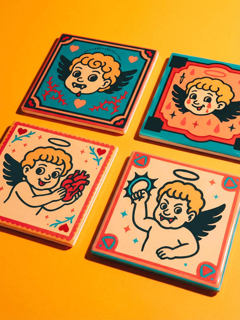 Set of four square ceramic coasters featuring a vampire cupid design in a pastel goth and traditional tattoo art style. The first coaster shows a fanged cherub on a teal background with red vines. The second features a cherub crying blood tears on a red background with daggers. The third depicts a cherub holding an anatomical heart on a peach background. The fourth shows a cherub with a spiked ring. Glossy glazed finish with cork backing. Ideal for spooky home decor and anti-valentine gifts.