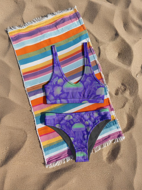 High-waisted cheeky bikini bottoms in a bold purple jellyfish print with iridescent greens and sea-inspired pastels. Made of 81% recycled REPREVE polyester and 19% LYCRA XTRALIFE, these bottoms offer UPF 50+ protection, double-layer construction, and a flattering silhouette. Sizes XS to 3XL. Perfect for festivals, beach days, and summer raves.