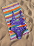 Bralette-style bikini top featuring a high neckline and vibrant jellyfish print in iridescent purples, blues, and greens on a lilac background. Made of recycled polyester and LYCRA XTRALIFE, this double-layered swim top includes removable padding, UPF 50+ protection, and is available in sizes XS to 3XL. Great for raves, beach days, and summer festivals.