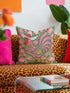 Square throw pillow cover with a printed faux embroidery design of a rooster wearing a white cowboy hat with red stars on a grass green background. The western chicken has a red comb and wattle, yellow beak and feet, and layered feathers in pink, green, orange, blue, and yellow with a rainbow striped tail. Pink and red flowers with yellow centers frame the bird. The stitched look is a flat 2D print on a smooth linen feel polyester cover with a hidden zipper, not raised embroidery.