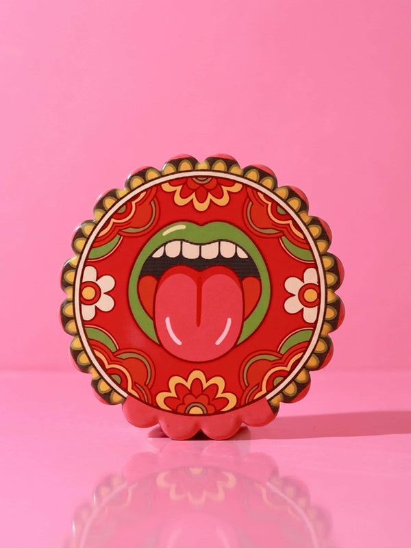 Round ceramic coaster with scalloped edges featuring a vibrant pop art design of an open mouth with green lips and a red tongue sticking out. The background is a bright red with psychedelic floral swirls in yellow orange and green. The surface is glossy glazed ceramic. The back is made of cork to prevent slipping. This maximalist decor piece fits retro 70s funky and weirdcore aesthetics. It is a bold statement piece for coffee tables. The design is colorful and eclectic dopamine decor.