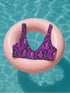 Psychedelic crystal bikini top featuring a vivid print of pink and purple crystals with wavy neon accents on a black background. Sports bra-style top with a scoop neckline, wide shoulder straps, and removable padding. Made of recycled polyester and LYCRA XTRALIFE with UPF 50+ sun protection. Available in sizes XS to 3XL. Double-layered construction with a snug, secure fit. Sustainable swimwear top for rave, beach, or summer festival wear.