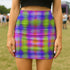 A woman wearing a colorful, patterned mini skirt stands in a grassy field.