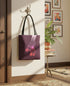 a purple tote bag hanging on a wall, with a potted plant and framed artwork in the background.