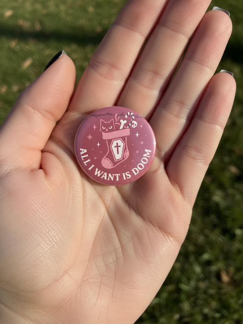 Set of 4 1.75 inch round pastel goth holiday pinback buttons. 1: Light pink with Baphomet head in wreath reading Merry Hexmas Hail Yourself. 2: Dark mauve with skull mistletoe reading Kiss Me or Perish. 3: Dark mauve with coffin stocking and black cat reading All I Want is Doom. 4: Light pink with cute Baphomet holding a sack reading Naughty on Purpose. All feature durable tinplate construction, high gloss laminate finish, and a secure metal safety pin back.