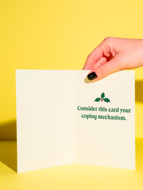 A 5x7 alternative holiday card with a white background and bold, punk-inspired typography. The text reads "Merry Crisis Happy New Fear" in dark green and red. The design features graphic elements like holly, stars, and safety pins, giving it a sarcastic, goth aesthetic. The inside message says "Consider this card your coping mechanism." This snarky, dark humor greeting card is perfect for a funny, unconventional Christmas, capturing a mental health humor and anti-capitalist vibe.