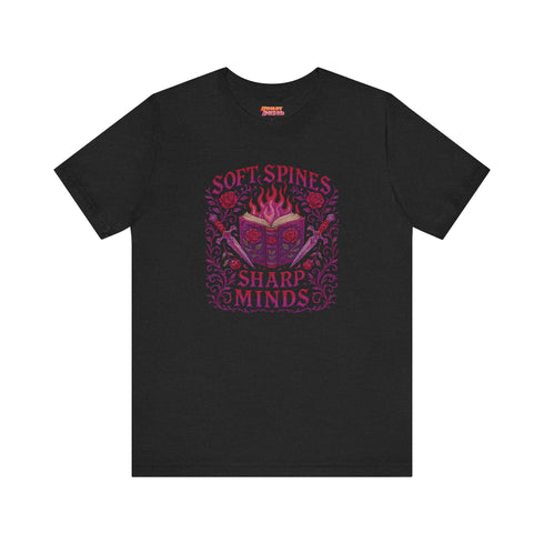 Unisex black t-shirt featuring a faux-embroidered design of a flaming open book with roses and dual daggers, surrounded by gothic flourishes and text that reads “Soft Spines, Sharp Minds.” Printed in vivid pink and red tones with ornate detailing. Available in 100% cotton or vintage-feel cotton/poly blend, sizes S–3XL. Perfect for goth book lovers, alt fashion fans, and anyone who blends brains with rebellion.