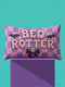 Pastel goth lumbar pillow, 20 by 12 inches, with a pink and lavender purple wavy checkerboard background. The words Bed Rotter appear in dripping pink bubble letters with a faux embroidery thread texture and black outlines. Two black bats with pink stitch details flank the text, and a black bow with a pink heart center sits below. Double sided flat print that mimics raised embroidery on linen feel polyester with a hidden zipper, insert included.