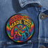 Round glossy pinback button measuring 2.25 inches featuring a vibrant rainbow psychedelic swirl with retro-style text that reads “Psychedelics Made Me Gay.” The background is a mix of rainbow waves and sparkles, with bold, colorful typography in orange, yellow, and blue. Made from durable tinplate with a safety pin backing, scratch-resistant mylar coating, and a high-gloss finish. Ideal for jackets, backpacks, or pride festival accessories.