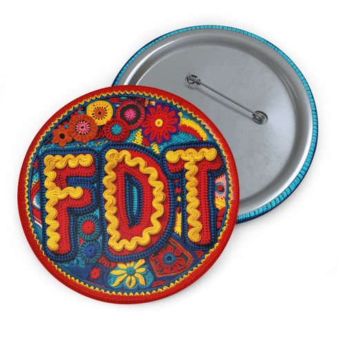 Round pinback metal button featuring an embroidered-style design on a vibrant, multicolored background. The bold, textured letters "FDT" are prominently displayed in red with intricate golden-yellow stitching details, outlined in dark blue. Surrounding the text is an ornate floral pattern with embroidered-style flowers in shades of red, orange, blue, and yellow, densely arranged for a rich, decorative effect. The outer edge is bordered with a zigzag stitching effect in red and blue. The button's back is sil