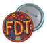 Round pinback metal button featuring an embroidered-style design on a vibrant, multicolored background. The bold, textured letters "FDT" are prominently displayed in red with intricate golden-yellow stitching details, outlined in dark blue. Surrounding the text is an ornate floral pattern with embroidered-style flowers in shades of red, orange, blue, and yellow, densely arranged for a rich, decorative effect. The outer edge is bordered with a zigzag stitching effect in red and blue. The button's back is sil
