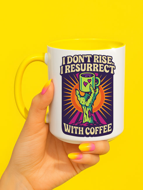 White ceramic coffee mug with red handle and interior, featuring a bold design of a zombie hand holding a coffee cup with the text “I Don’t Rise, I Resurrect With Coffee” in white and purple, accented with a neon green hand and orange sunburst background.
