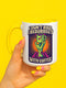 White ceramic coffee mug with red handle and interior, featuring a bold design of a zombie hand holding a coffee cup with the text “I Don’t Rise, I Resurrect With Coffee” in white and purple, accented with a neon green hand and orange sunburst background.
