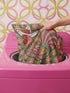 Square throw pillow cover with a printed faux embroidery design of a rooster wearing a white cowboy hat with red stars on a grass green background. The western chicken has a red comb and wattle, yellow beak and feet, and layered feathers in pink, green, orange, blue, and yellow with a rainbow striped tail. Pink and red flowers with yellow centers frame the bird. The stitched look is a flat 2D print on a smooth linen feel polyester cover with a hidden zipper, not raised embroidery.
