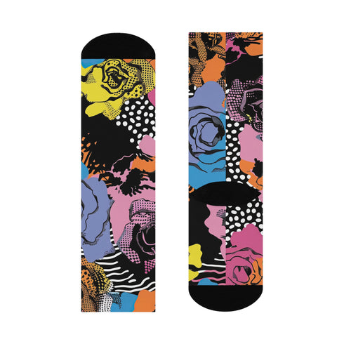 Colorful crew-length socks with a vibrant floral pop-art collage design, featuring abstract roses in yellow, lavender, pink, and orange tones, polka dots, and zebra stripes on a black background.