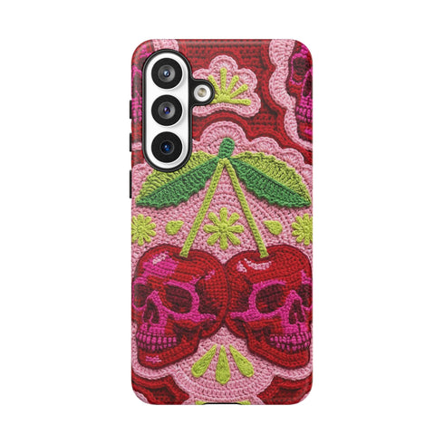 Dual layer matte phone case with a high fidelity 2D print that creates a hyper realistic faux crochet and knit illusion. The central design shows two conjoined cherries styled as bright pink and burgundy human skulls with lime green stems and leaves. The background is a detailed scalloped lace doily pattern in hot pink, deep red, and lime green. Matte finish shell with a black inner TPU lining, precise camera cutout, and open ports. Pastel goth macabre alt fashion phone accessory, made to order.
