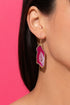 A close-up view of a woman's ear wearing a pair of earrings with a pink and white stone.