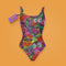 A colorful one-piece swimsuit features a vibrant, quirky pattern with cherries, cartoon eyes, and playful designs on a dark background.