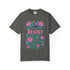 Comfort Colors 1717 unisex garment-dyed t-shirt featuring a front floral graphic with the word RESIST in pink block letters surrounded by green vines, purple roses, skulls, moons, and daggers. Made of soft-washed 100% ring-spun cotton with tubular knit construction, available in sizes S to 4XL.