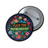 Circular black pinback button with "FUCK THE PATRIARCHY" in orange and mint green text, surrounded by embroidery-style flowers in pink, blue, and red with green foliage and blue border. Folk art feminist protest pin with glossy finish and safety pin backing in 2" and 3" sizes.
