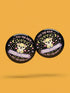 A collection of four retro-style 1.75 inch pinback buttons featuring the text "Tax the Rich" and "Pet the Dogs." Designs include: 1) A black pin with a crystal ball and gold filigree, 2) A pink pin with floral accents and a happy dog, 3) A black pin with a spooky chihuahua holding a bone, and 4) A black pin with a cute devil-horned puppy and lavender banner. High-gloss finish with psychedelic 70s typography. Perfect for battle vests or backpacks. Funny anti-capitalist dog lover gift.