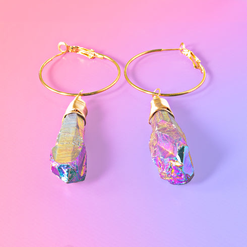a pair of gold hoop earrings with a pink background