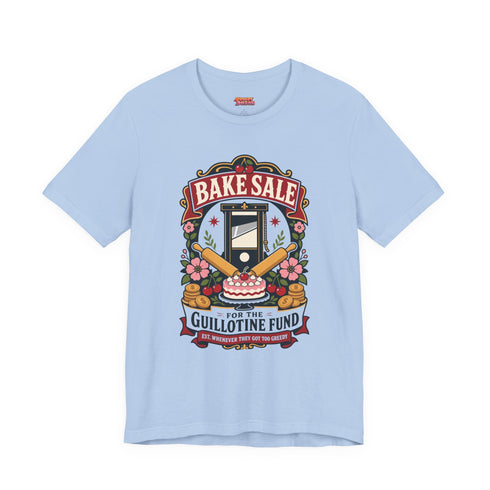 A short sleeve unisex crewneck t-shirt featuring a vintage style emblem graphic centered on the chest. The design features a red banner reading BAKE SALE above a black guillotine. Two crossed wooden rolling pins sit below the guillotine, above a layered pink and white cake with a cherry. The graphic is flanked by pink flowers, cherries, and stacks of gold coins. A bottom banner reads FOR THE GUILLOTINE FUND EST. WHENEVER THEY GOT TOO GREEDY. The shirt comes in light pink, cream, and blue.