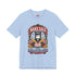 A short sleeve unisex crewneck t-shirt featuring a vintage style emblem graphic centered on the chest. The design features a red banner reading BAKE SALE above a black guillotine. Two crossed wooden rolling pins sit below the guillotine, above a layered pink and white cake with a cherry. The graphic is flanked by pink flowers, cherries, and stacks of gold coins. A bottom banner reads FOR THE GUILLOTINE FUND EST. WHENEVER THEY GOT TOO GREEDY. The shirt comes in light pink, cream, and blue.