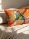 Rectangular 20x12 inch lumbar pillow cover in bright orange featuring printed faux embroidery of a green frog wearing a pink cowgirl hat and pink cowboy boots, lounging on a golden yellow crescent moon shaped like a peeled banana, surrounded by cream and gold sparkle stars and retro wavy stripes. Whimsical cowboy frog design printed on both sides with a hidden zipper, crafted from soft linen look polyester in a funky 70s retro style.