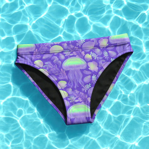 High-waisted cheeky bikini bottoms in a bold purple jellyfish print with iridescent greens and sea-inspired pastels. Made of 81% recycled REPREVE polyester and 19% LYCRA XTRALIFE, these bottoms offer UPF 50+ protection, double-layer construction, and a flattering silhouette. Sizes XS to 3XL. Perfect for festivals, beach days, and summer raves.