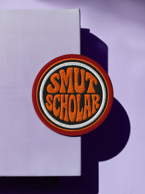 a circular patch with the text "SMUT SCHOLAR" in orange and black colors.