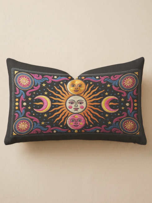 Rectangular 20x12 inch lumbar pillow cover in black featuring printed faux crewel embroidery of a large orange sunburst with a cream face, flanked by pink and yellow crescent moons, a golden moon face above and a pink moon face below, gold stars, blue dots, magenta and blue baroque scroll flourishes, and four corner medallions with golden flowers. Whimsigoth celestial design printed on both sides with a hidden zipper, crafted from soft linen look polyester.