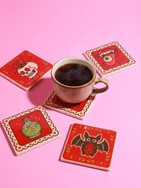 Set of four square glazed ceramic coasters featuring a vibrant pastel goth and creepy cute design. These functional art pieces show a spooky yet playful aesthetic perfect for alternative home decor. The coasters have a glossy wipe-clean finish and a non-slip cork backing to protect furniture surfaces from hot and cold beverages. Ideal for maximalist coffee tables, witchy desks, or as a unique housewarming gift for horror fans who love retro 70s and dopamine decor styles.