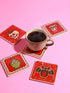 Set of four square glazed ceramic coasters featuring a vibrant pastel goth and creepy cute design. These functional art pieces show a spooky yet playful aesthetic perfect for alternative home decor. The coasters have a glossy wipe-clean finish and a non-slip cork backing to protect furniture surfaces from hot and cold beverages. Ideal for maximalist coffee tables, witchy desks, or as a unique housewarming gift for horror fans who love retro 70s and dopamine decor styles.