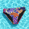 Psychedelic bikini bottom with multicolored tiger print on a neon leopard background; mid-rise cut with black lining and vibrant color blocking in purple, blue, pink, orange, and cream; made of recycled polyester and spandex blend with cheeky fit.