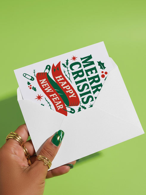 A 5x7 alternative holiday card with a white background and bold, punk-inspired typography. The text reads "Merry Crisis Happy New Fear" in dark green and red. The design features graphic elements like holly, stars, and safety pins, giving it a sarcastic, goth aesthetic. The inside message says "Consider this card your coping mechanism." This snarky, dark humor greeting card is perfect for a funny, unconventional Christmas, capturing a mental health humor and anti-capitalist vibe.