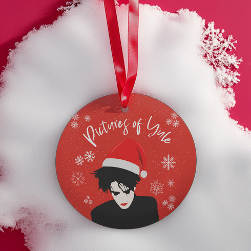 Round red metal Christmas ornament featuring Robert Smith silhouette in black with white Santa hat, red lips, and snowflake details. Text reads "Pictures of Yule" in white script.