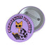 Purple button pin featuring a yellow cat wearing sunglasses and reading a book, with "Purrfectly Bookish" text curved around the edge