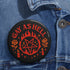 Round glossy pinback button measuring 2.25 inches with bold red graphic design on a black background. Text reads “Gay As Hell” above a red pentagram surrounded by flames, stars, roses, and candles. Made of tinplate with a safety pin back and a scratch-resistant mylar finish. The button features a high-gloss surface and is lightweight and durable, perfect for jackets, bags, or accessories.