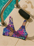 Psychedelic animal print bikini top with multicolor tiger pattern in neon pink, purple, orange, and blue, made of stretchy recycled fabric with wide shoulder straps and scoop neckline.