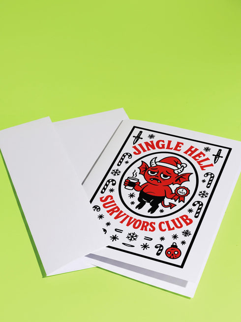 A 5x7 pearlescent shimmer folded greeting card featuring the Jingle Hell Survivors Club design. The front is a illustration of a grumpy red devil imp character, wearing a small Santa hat, holding a coffee cup, and a circular 'I Tried' merit badge. The overall aesthetic is maximalist dark humor and spooky cute. This anti-Christmas card is perfect for those needing relief from holiday stress. Inside text references surviving tolerable relatives, strong eggnog, and merciful hangovers.