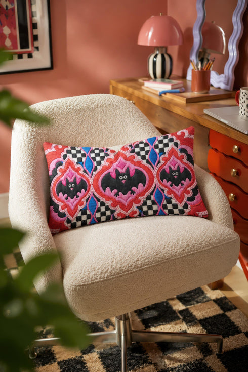 Rectangular 20x12 inch lumbar pillow cover in red featuring printed faux embroidery of three black bats with white eyes and pink noses, each framed in an ornate ogee medallion with pink flame stitch centers, black and white checkerboard accents, and cobalt blue diamonds. Whimsigoth damask bat design printed on both sides with a hidden zipper, crafted from soft linen look polyester for spooky maximalist home decor.