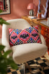 Rectangular 20x12 inch lumbar pillow cover in red featuring printed faux embroidery of three black bats with white eyes and pink noses, each framed in an ornate ogee medallion with pink flame stitch centers, black and white checkerboard accents, and cobalt blue diamonds. Whimsigoth damask bat design printed on both sides with a hidden zipper, crafted from soft linen look polyester for spooky maximalist home decor.