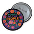 Embroidered-style pinback button featuring the phrase "POWER TO THE PEOPLE" in bold, multicolored satin-stitch letters—green, purple, and orange—framed by a vivid circular floral wreath. Pink, red, and purple flowers with leafy greens radiate around the text. Design has a handcrafted, folk-art feel with a transparent background.