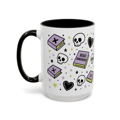 The Gothic Read Dangerously Mug Accent Coffee Mug (11, 15oz) features a white ceramic design with black handle, pastel books, skulls, hearts, and stars—one book reads READ DANGEROUSLY. A stylish, functional gift for any book lover.