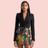 A woman wearing a black blazer and a colorful floral skirt, with a black handbag on her hip.