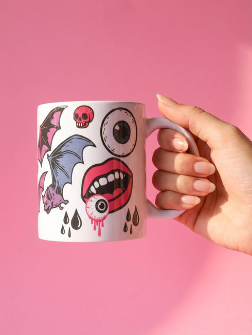 White porcelain 11oz mug and matching 4x4 inch square ceramic coaster set featuring a vibrant, maximalist full-wrap pattern. The design illustrates glossy pink vampire lips with white fangs and red tongues, interspersed with floating eyeballs, purple bats, and small pink skulls against a white background. The mug features a glossy finish and C-handle. The coaster has a matching glazed ceramic top and a brown cork backing. High-contrast pop-art style with pink, purple, and black details.