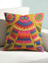 A square faux embroidery pillow featuring a brightly colored maximalist design against a mustard yellow background. In the center stands a stylized, furry Bigfoot or Sasquatch figure rendered in vibrant layers of pink, orange, blue, and lime green with a blue face and yellow eyes. The central creature is surrounded by large, detailed symmetrical pink and blue flowers and leaves. The flat printed fabric creates a highly realistic optical illusion of dimensional crewel embroidery stitches.