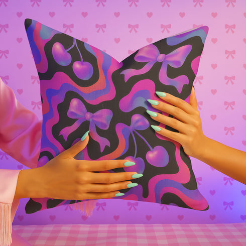 Throw pillow with a black background and a vibrant Y2K-inspired design featuring gradient cherries and shiny bows. The pattern includes pink, purple, orange, and blue psychedelic squiggles. The square pillow is displayed on a pink chair, bright blue couch, and outdoors with camping gear, emphasizing its bold, girly, and playful aesthetic. Perfect for dopamine decor, Gen Z bedrooms, or quirky home styling.