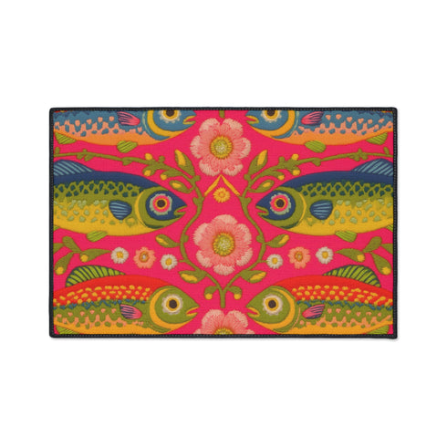 Rectangular indoor outdoor doormat featuring a vibrant hot pink background with a symmetrical maximalist pattern. The design showcases stylized sardines in yellow, lime green, and cobalt blue swimming horizontally towards a central vertical axis of blooming pale pink flowers and green vines. The imagery mimics the texture of vintage needlepoint embroidery but is a flat print on polyester. The mat is framed by a sleek black trim and features a non-slip rubber backing for safety.